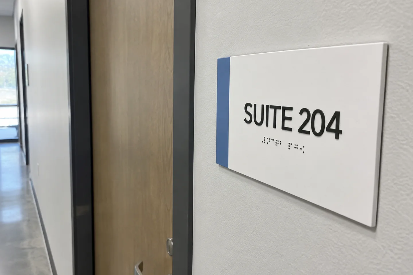 Daylight concept visualization of a simple Suite 204 ADA room sign with tactile lettering and Braille